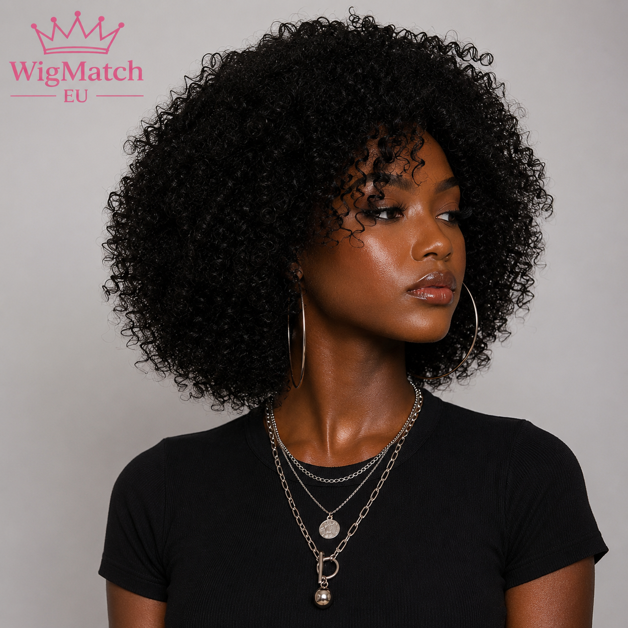 woman wearing a black afro kinky curly human hair wig, looking to the right in a side profile, with dark chocolate skin, a black top, and a light gray studio background,wigmatch EU.